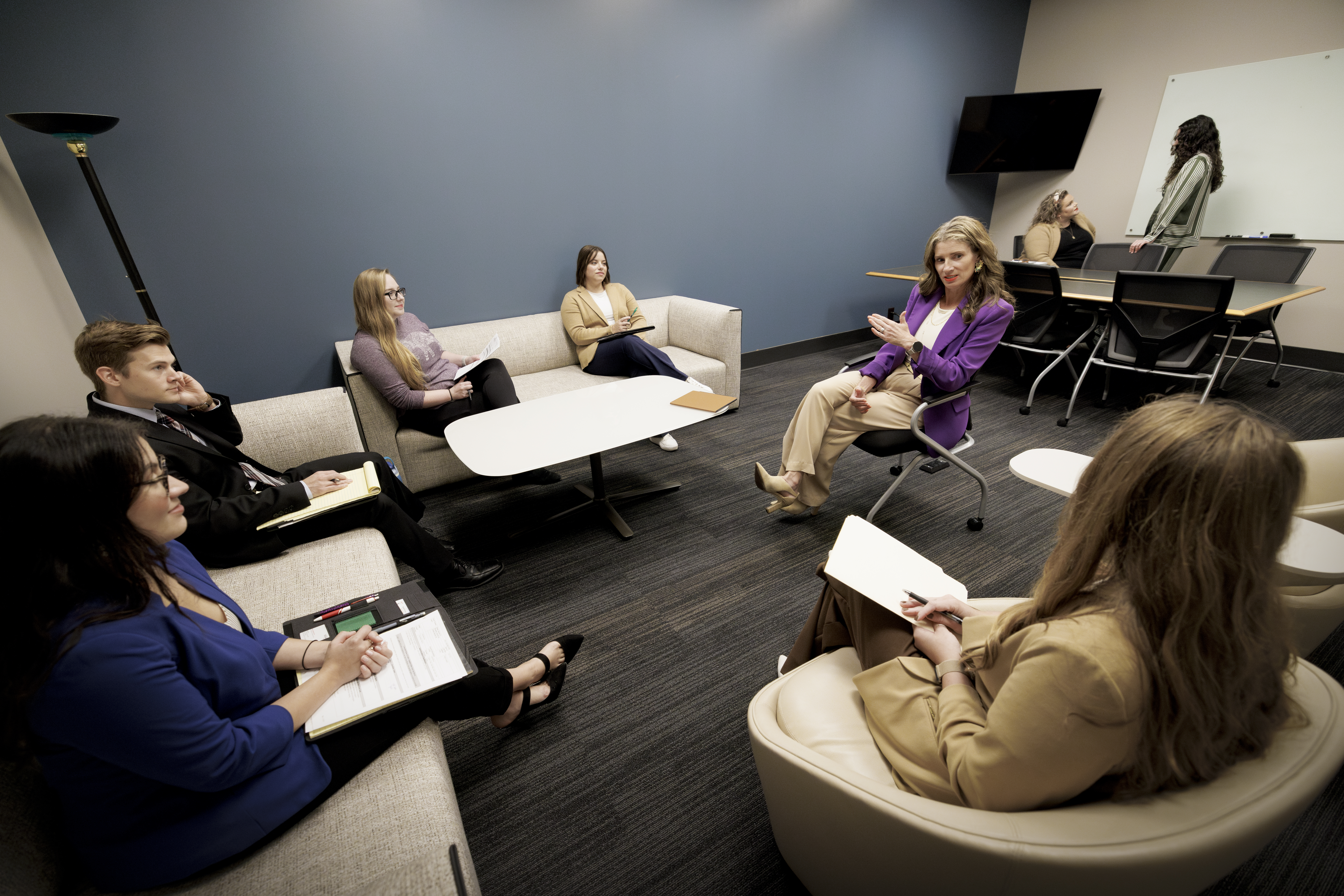 Professor sitting and speaking with 5 students