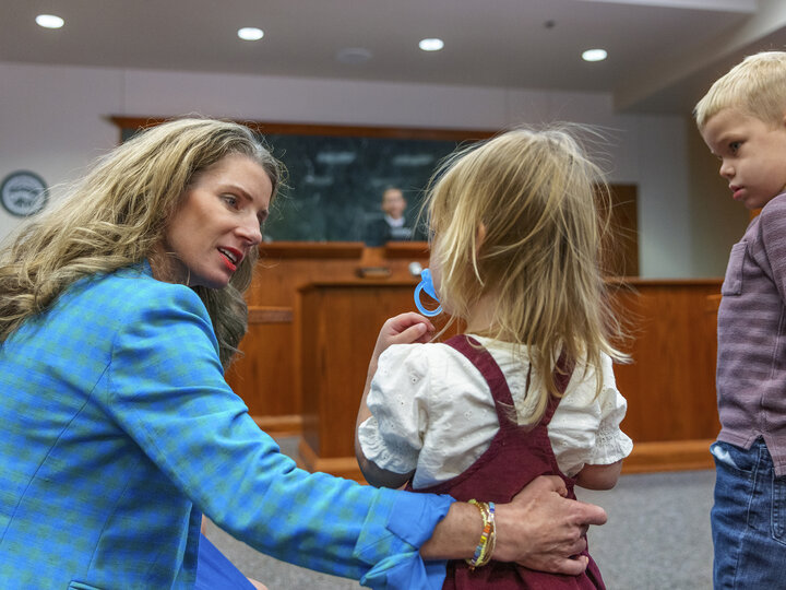 Woman kneeling talking to two children in courtroom